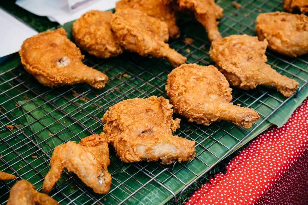 Golden crispy fried chicken served on banana leaves in a Bangkok street market.