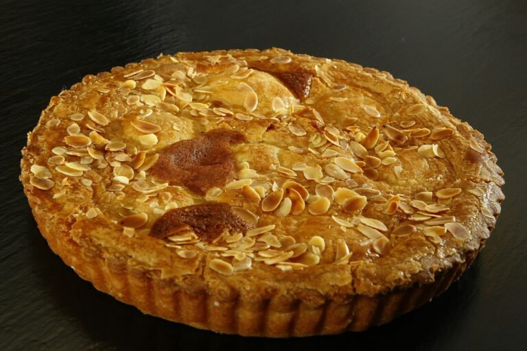 Delicious homemade almond tart with golden crust on a dark background.